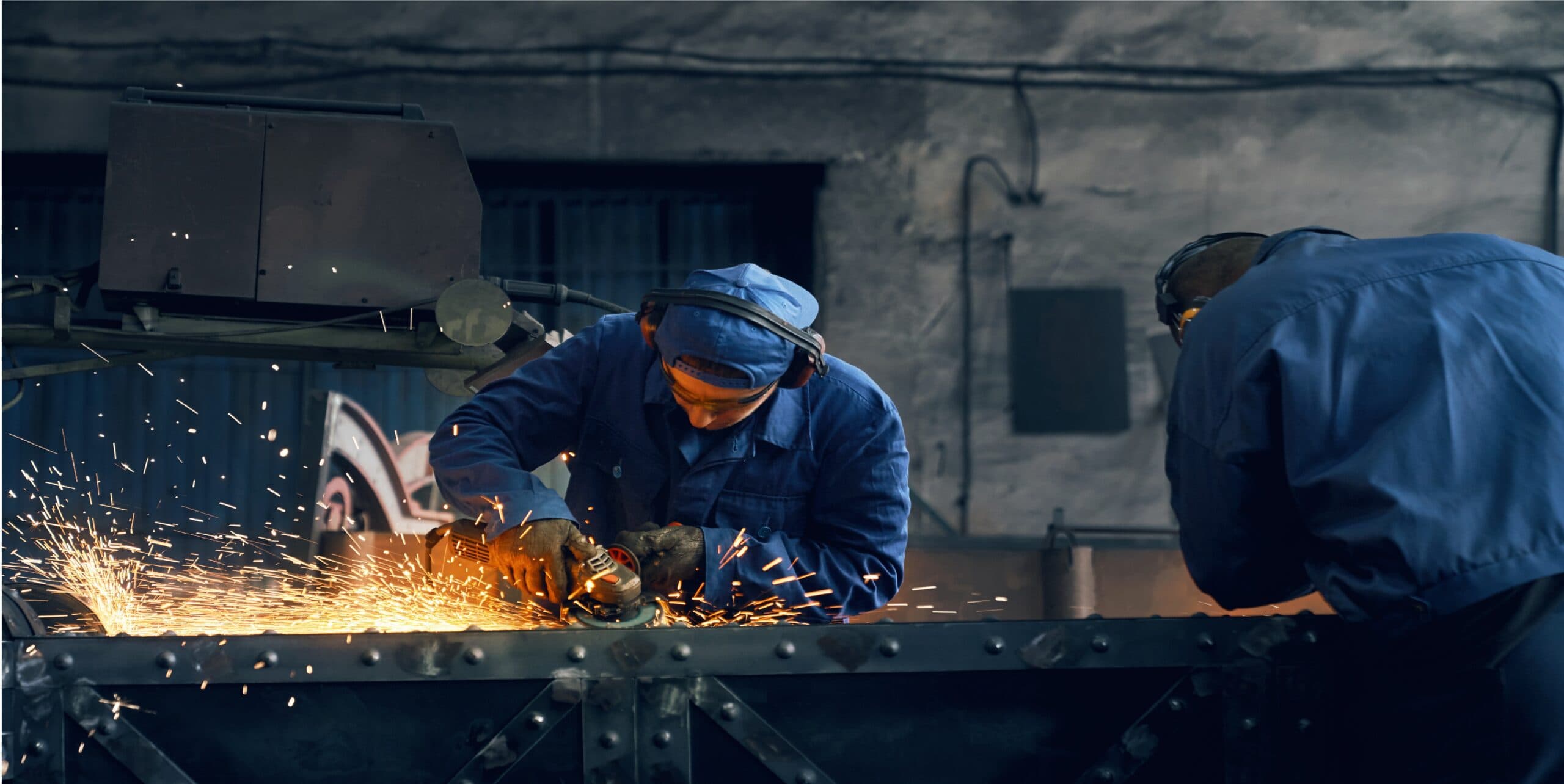 Two workers fabricating metal gates in a smithy